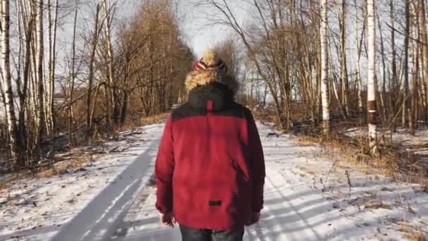 一个人一个人在森林里的一条冬天的路上走着 — 图库视频影像