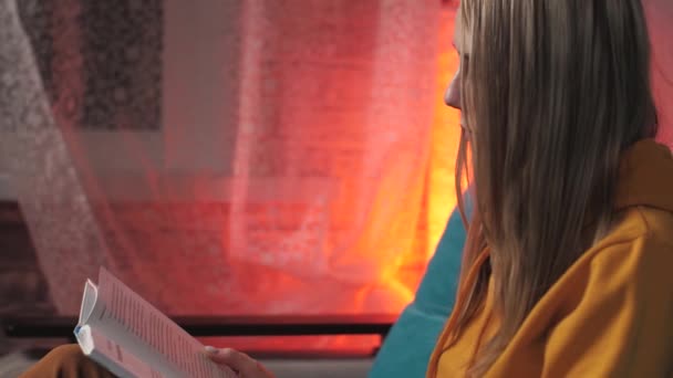 Girl Reading Book Sitting Couch Orange Light Evening — Stock Video