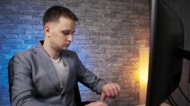 Ceketli adam bilgisayarda çalışıyor, ev ofisinde, uzaktan kumanda işinde.