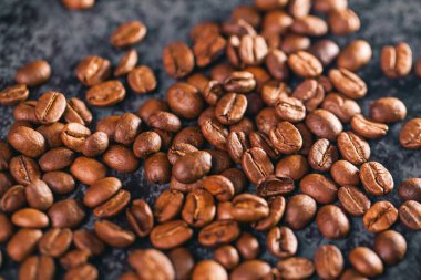 Kahve çekirdekleri gri bir zemine saçılmış.