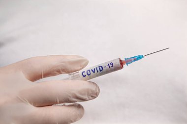 Laboratuvarda bir doktor ya da bilim adamı COVID-19 Coronavirus testlerinin yapıldığı bir şırınga tutuyor.