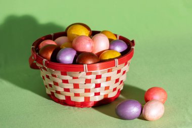 Yeşil dokuya izole edilmiş sepetteki Paskalya yumurtası.