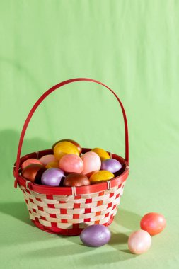 Yeşil dokuya izole edilmiş sepetteki Paskalya yumurtası.