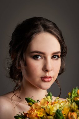 Gri arkaplanda fotostudyosu olan beyaz elbiseli güzel bir gelin.