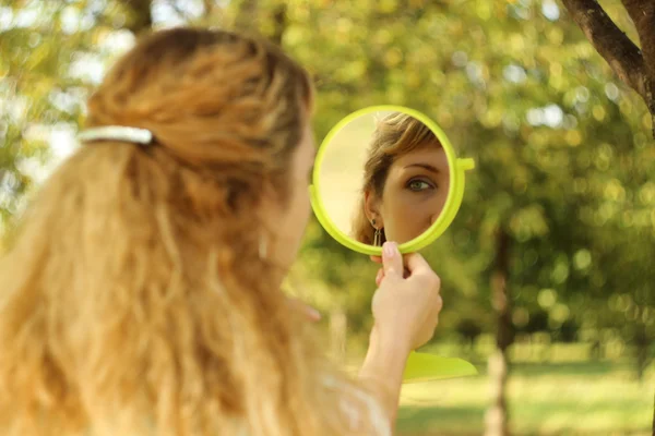 Jeune belle fille regarder dans le miroir dans le parc.Conception douce et floue — Photo