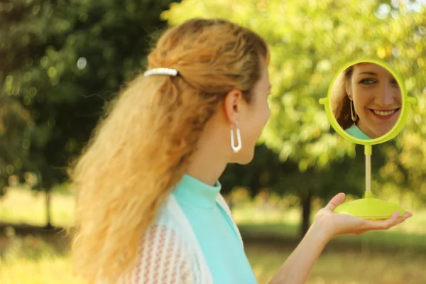 Giovane bella ragazza guardarsi allo specchio nel park.Soft e concezione sfocata — Foto Stock