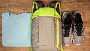 Spor ayakkabı, sırt çantası, t-shirt yakın çekim için en iyi görünümü, ahşap bir arka plan ayarlamak.