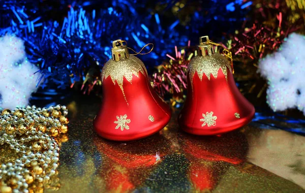 Dois belos sinos vermelhos em um fundo brilhante closeup com guirlandas brilhantes multicoloridas e flocos de neve — Fotografia de Stock