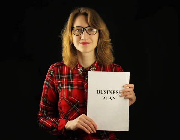Γκρο πλαν όμορφη κοπέλα σε ένα κόκκινο καρό πουκάμισο κρατώντας χαρτί στα χέρια της με ένα επιχειρηματικό σχέδιο για την εργασία — Φωτογραφία Αρχείου