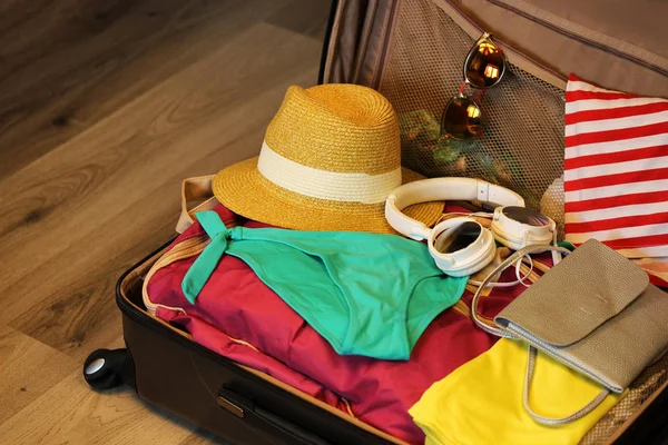 Verzamelde koffer voor reizen. Koffer in open uitzicht close-up met dingen om uit te rusten op een houten achtergrond — Stockfoto