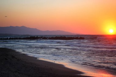 Yaz aylarında güzel pembe günbatımı denizin kenarında. Arka planda uçup uçak