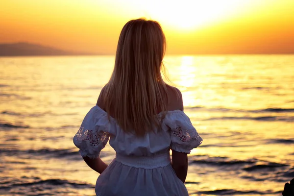 Joven hermosa chica rubia sentada de cerca cerca del mar al atardecer —  Fotos de Stock