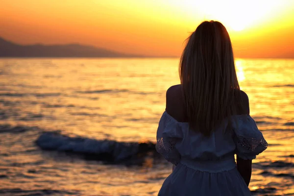Joven hermosa chica rubia sentada de cerca cerca del mar al atardecer —  Fotos de Stock