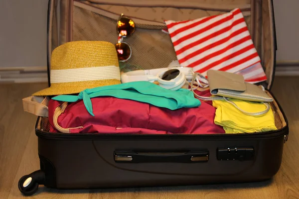 Shromážděné kufr pro cestování. Kufr v očích closeup s věcmi na dřevěné pozadí — Stock fotografie