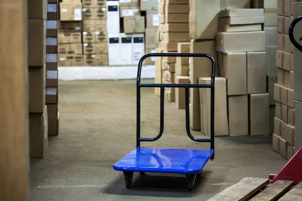 Warehouse with goods in boxes and trolleys for transportation of goods close-up — Stock Photo, Image