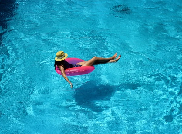 Menina bonita nova está nadando na piscina com um círculo rosa — Fotografia de Stock