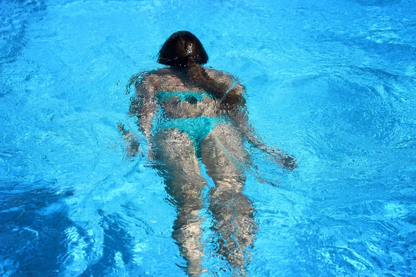 Mooi meisje zwemmen onder water in het zwembad met blauw water — Stockfoto