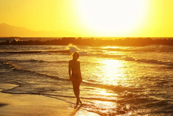 Silueta de joven hermosa chica de cerca cerca del mar al atardecer —  Fotos de Stock