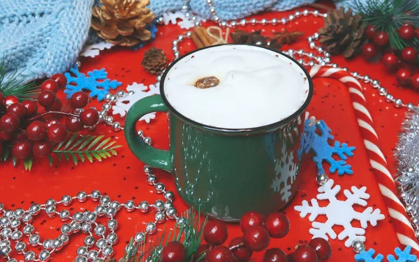 Green cappuccino mug with Christmas decorations on a red background — Stock Photo, Image