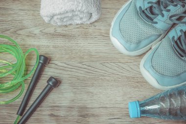 Spor için hazır: spor ayakkabıları, su şişesi, beyaz havlu ve ahşap arka planda atlamak için ip..