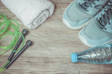 Spor için hazır: spor ayakkabıları, su şişesi, beyaz havlu ve ahşap arka planda atlamak için ip..