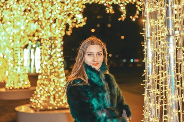 Joven chica bonita en abrigo de piel verde al aire libre en el fondo brillante — Foto de Stock