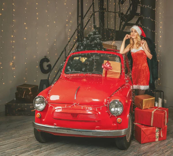 Junge hübsche Schneemädchen auf dem Hintergrund der festlichen Dekoration und ein rotes Auto mit Geschenken und Weihnachtsbaum — Stockfoto