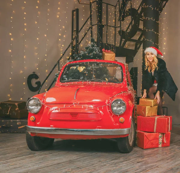 Mladá hezká sněhová panna na pozadí slavnostní dekorace a červené auto s dárky a vánoční stromeček — Stock fotografie