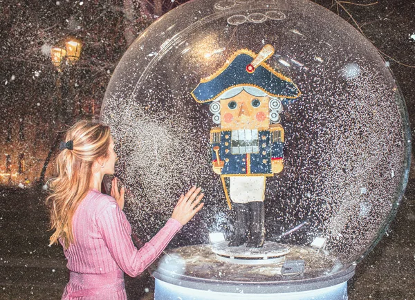 Balle magique avec un casse-noisette à l'intérieur et une fille de ballerine dans une robe rose brillant à côté sur un fond neigeux — Photo