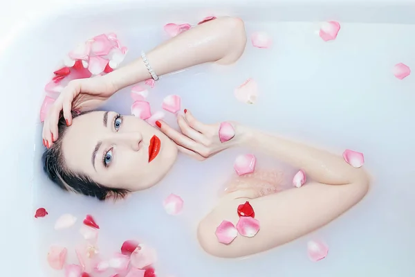 Giovane ragazza sexy che prende un bagno di latte con petali di rosa — Foto Stock