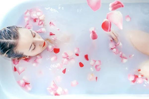 Młoda sexy dziewczyna biorąc a mleko kąpiel z płatki róż zbliżenie — Zdjęcie stockowe