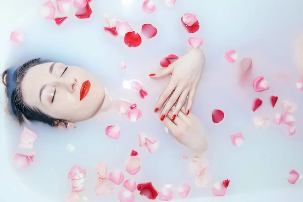 Giovane ragazza sexy che prende un bagno di latte con petali di rosa primo piano — Foto Stock