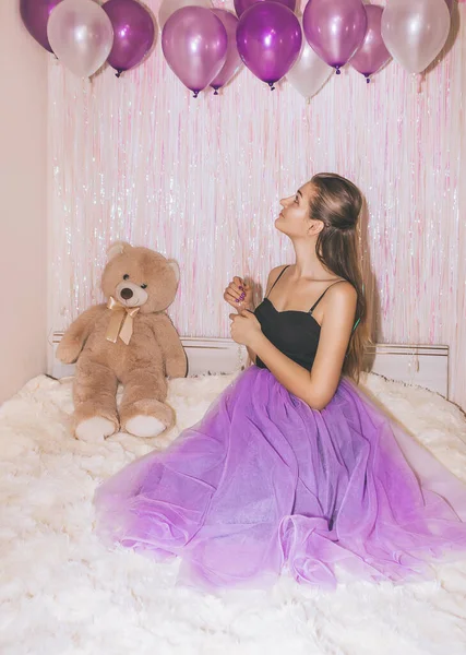 生日女孩穿着紫色裙子特写 年轻漂亮的女人手里拿着紫色的空气球坐在床上 — 图库照片