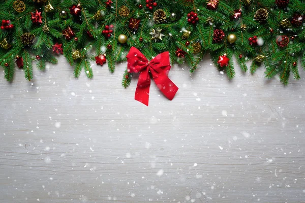 Frontera de Navidad - Ramas de abeto y ornamento en tablón de madera con cinta roja —  Fotos de Stock