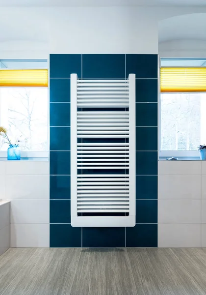 White towel dryer on a blue tiled bathroom wall