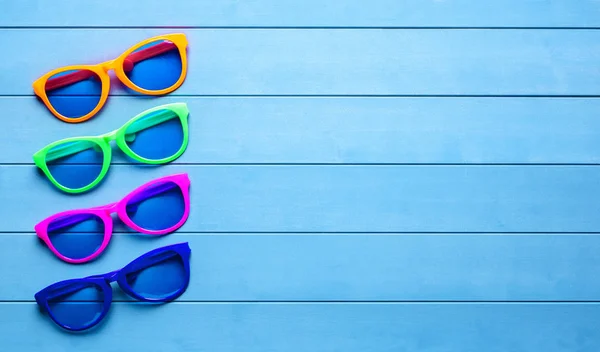 Collection of colorful sunglasses on blue wooden background