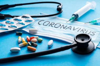 Mavi arka planda koruyucu yüz maskesi, haplar, şırıngalar ve steteskop, Novel Coronavirus 2019-ncov veya Wuhan Coronavirus 'a karşı. Hijyen ve Sağlık Hizmetleri kavramı