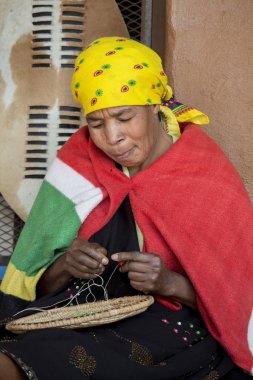 Etnik giysiler içinde güzel bir Afrikalı Zulu kadın bir boncuk takı dokuma. Geleneksel el yapımı kostüm, headdress ve battaniye.
