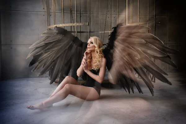 Blond kvinna med svarta vingar i en bur. Angel, mystik — Stockfoto