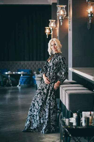 Mujer en vestido blanco y negro posando en restaurante — Foto de Stock