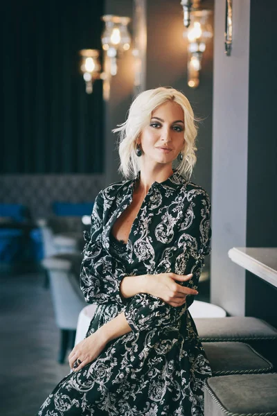 Mujer en vestido blanco y negro posando en restaurante — Foto de Stock