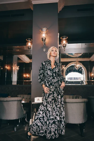 Mujer en vestido blanco y negro posando en restaurante — Foto de Stock