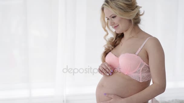 ランジェリーで妊娠中の女性は、彼女の腹を愛撫.今後のママ — ストック動画