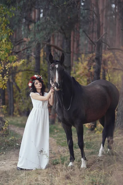 Jesienny portret romantyczny kobiety z kwiatami we włosach, w pobliżu z koniem — Zdjęcie stockowe