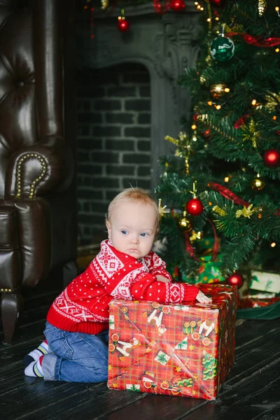 Petit garçon assis près des boîtes et l'ouverture des cadeaux de Noël — Photo
