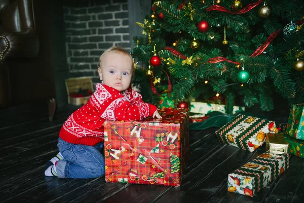 Petit garçon assis près des boîtes et l'ouverture des cadeaux de Noël — Photo