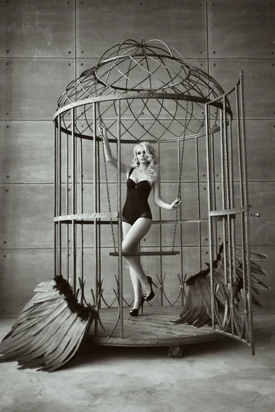 Blond kvinna med svarta vingar i en bur. Angel, mystik — Stockfoto