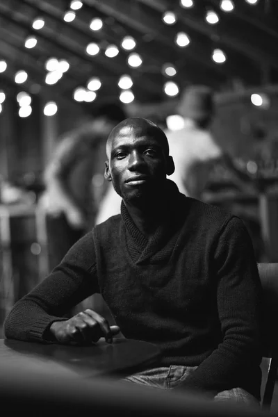 Un hombre guapo sentado en un cuarto oscuro. retrato sonrisa —  Fotos de Stock