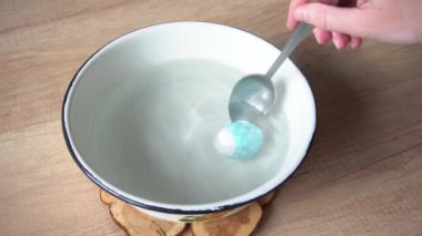 Paskalya bayramı için ev yapımı tavuk yumurtası dekoru. Plastik benekten yapılmış bir kase kaynamış su etiketi. Mavi noktalar.