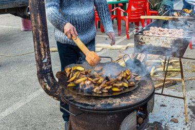 Patatesler büyük bir masada kızartılır. Bir adam tahta kaşıkla patates karıştırıyor. Büyük soba. Karnaval kutlaması. Bilogorotka. Ukrayna. Bahar Toplantısı, 25 Şubat 2017